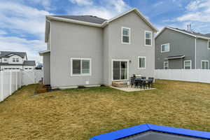 Back of property with entry steps, a fenced backyard, stucco siding, a lawn, and a patio area