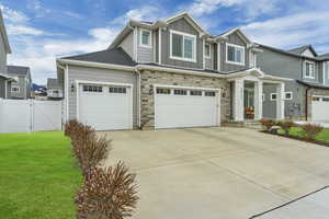 Craftsman-style home with concrete driveway, fence, board and batten siding, a front yard, and a gate