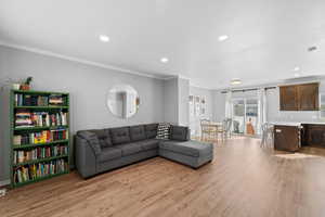 Living room with recessed lighting, light wood-style floors, and crown molding