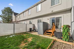 Rear view of house featuring stucco siding, a fenced backyard, and a lawn