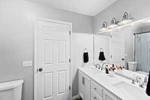 Master bathroom with toilet, a sink, and double vanity