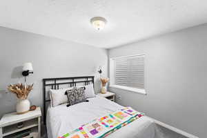 Bedroom with baseboards, carpet floors, and a textured ceiling