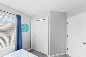 Carpeted bedroom featuring baseboards and a closet