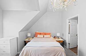 Bedroom featuring baseboards, lofted ceiling, and an inviting chandelier