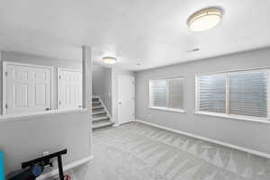 Interior space with baseboards, visible vents, stairway, and a textured ceiling
