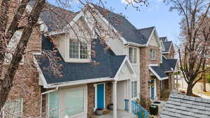 View of front of home featuring a shingled roof, stucco siding, and stone siding