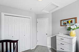 Bedroom with a closet, baseboards, carpet, and attic access