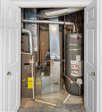 Utility room featuring strapped water heater