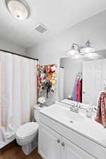 Full bathroom featuring toilet, vanity, wood finished floors, and visible vents