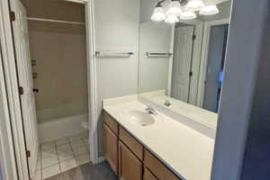 Bathroom with vanity, toilet, tile floors, and washtub / shower combination
