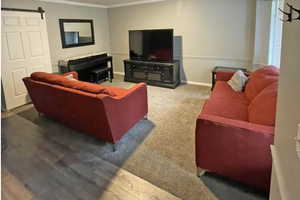 Living area featuring carpet and laminate flooring,  and a barn door to separate the kitchen