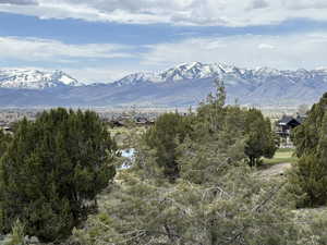 Property view of mountains, golf course pond and green