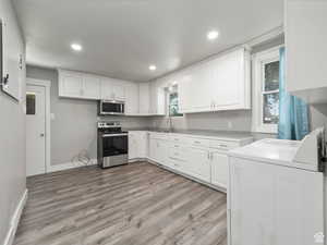 Kitchen with white cabinets, independent washer and dryer, a sink, and appliances with stainless steel finishes