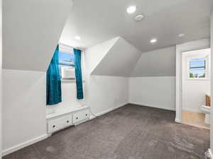 Additional living space with a wealth of natural light, carpet floors, baseboards, and a textured ceiling
