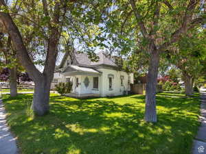 View of front of home featuring central AC, fence, roof with shingles, and a front yard