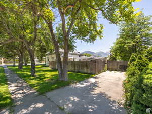 View of side of property with a yard, a mountain view, and fence