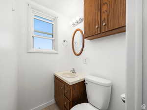 Half bathroom with toilet, vanity, baseboards, and tile patterned flooring