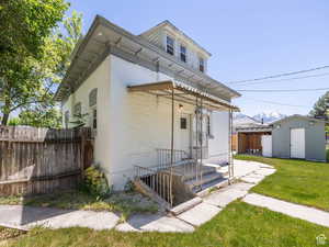 American foursquare style home featuring a lawn, an outdoor structure, fence, and brick siding