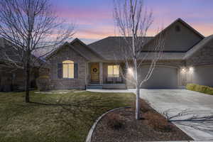 Single story home with a garage, concrete driveway, brick siding, roof with shingles, and a yard