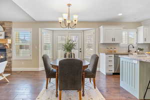 Dining space with baseboards, a fireplace, recessed lighting, dark wood finished floors, and a notable chandelier