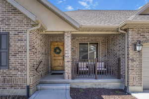 Doorway to property with brick siding and roof with shingles