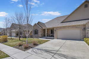 View of front of home with a front lawn, an attached garage, brick siding, and concrete driveway