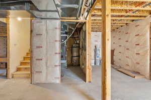Unfinished below grade area featuring water heater and stairs