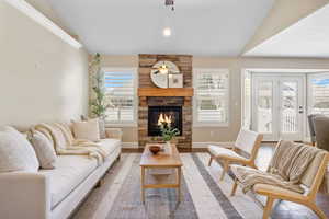 Living room with ceiling fan, vaulted ceiling, and a stone fireplace