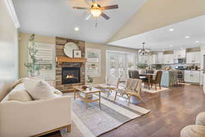 Living area featuring a fireplace, lofted ceiling, ceiling fan with notable chandelier, recessed lighting, and dark wood-style flooring