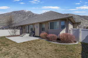 Back of property with stucco siding, a gate, a mountain view, and a yard