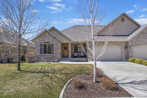 Ranch-style house featuring stucco siding, driveway, a front yard, brick siding, and a shingled roof