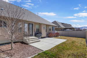 Back of property with stucco siding, roof with shingles, fence, a patio, and a yard