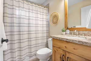 Bathroom featuring toilet, a shower/tub with shower curtain, and vanity