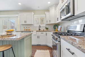 Kitchen with a healthy amount of sunlight, white cabinets, tasteful backsplash, and stainless steel appliances