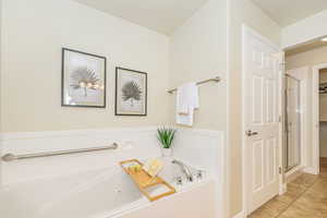Bathroom with tile patterned floors, a jetted tub, a walk in closet, and a shower stall