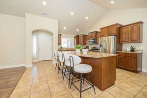 Kitchen featuring a center island, a breakfast bar, visible vents, light stone countertops, and appliances with stainless steel finishes