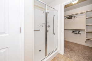 Full bathroom with baseboards, tile patterned flooring, a stall shower, and a walk in closet