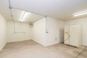 Garage with white refrigerator with ice dispenser and baseboards