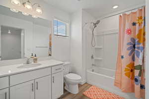 Full bathroom featuring wood finished floors, toilet, vanity, and shower / bath combo with shower curtain