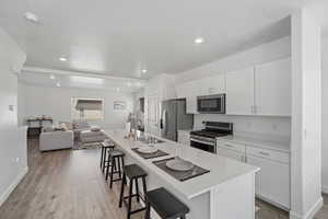 Kitchen with open floor plan, a kitchen bar, a sink, and stainless steel appliances
