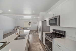 Kitchen featuring light countertops, dark wood finished floors, appliances with stainless steel finishes, a sink, and open floor plan