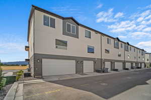 Back of property with central air condition unit, stucco siding, and an attached garage