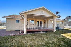 Back of property featuring brick siding, central AC, covered porch, and a yard