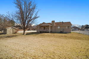 Rear view of house with a chimney, fence, a mountain view, and a yard
