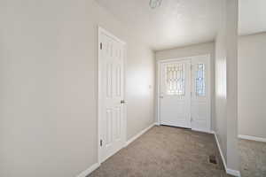 Carpeted entryway featuring baseboards and visible vents