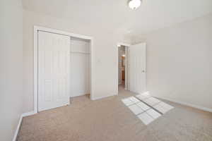 Unfurnished bedroom with a closet, baseboards, and light colored carpet