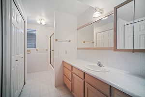 Bathroom with tile walls, a wainscoted wall, vanity, shower / bath combination with glass door, and tile patterned flooring