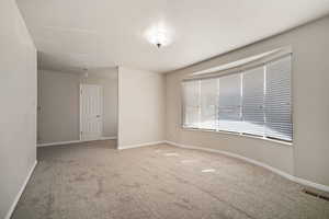 Empty room with carpet floors, baseboards, and visible vents