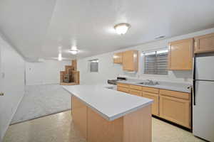Kitchen with light countertops, white appliances, a sink, visible vents, and light brown cabinets