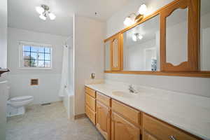 Bathroom featuring tile walls, visible vents, toilet, vanity, and wainscoting